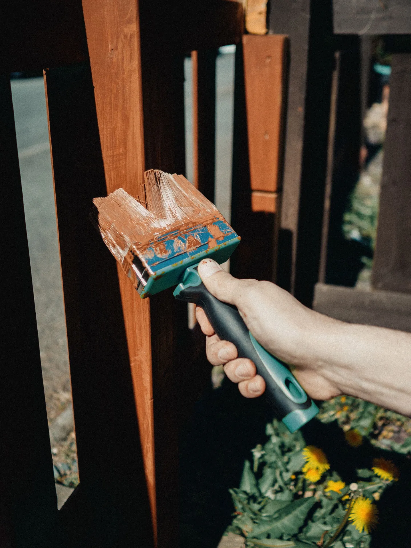 Hand staining a wooden fence with a brush outdoors